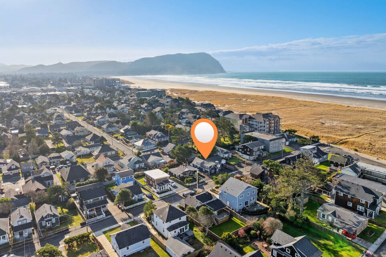 A residential area with houses, a beach, and a mountain in the background.