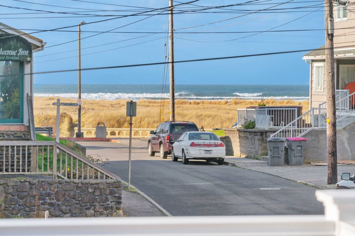 Una carretera costera con vista a la playa, un letrero de 'Avenue Inn' y coches estacionados.
