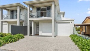 A modern two-story house with a garage, a balcony on the upper floor, and a well-maintained garden.