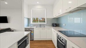A modern kitchen with white cabinetry, a built-in oven, a microwave, and a large window above the sink.