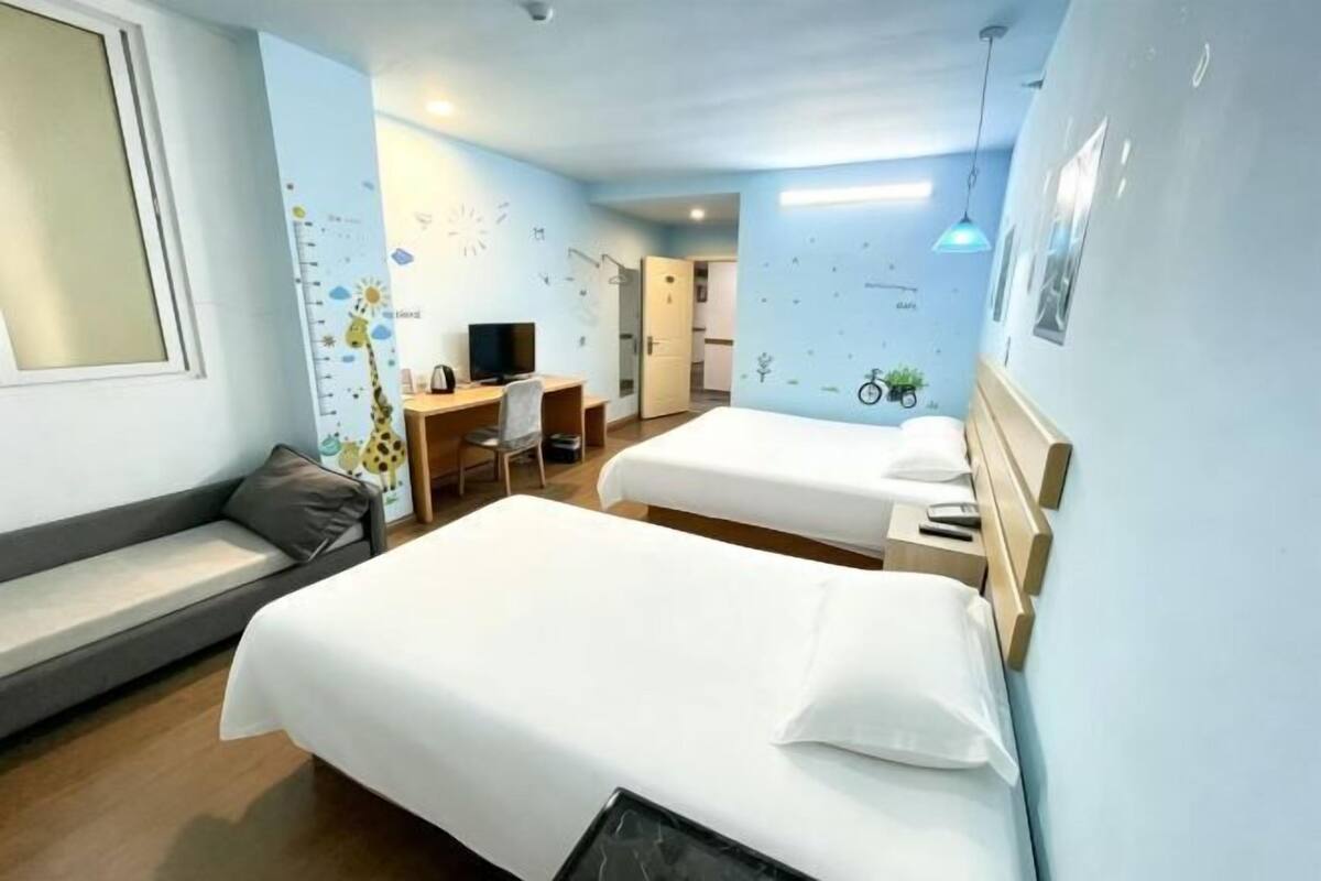 A hotel room with two beds, a desk, a chair, and a sofa.