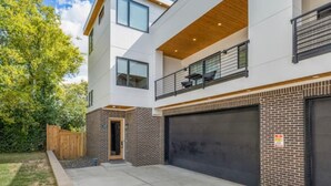 Un immeuble moderne à deux étages, doté d’un garage, d’un balcon et d’une façade en briques.