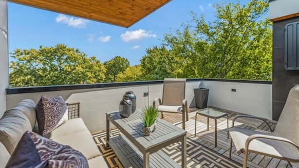 Une terrasse extérieure avec un canapé, des chaises, une table et une plante en pot.