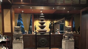 A traditional Japanese interior with a stone water feature, wooden paneling, and a tiled floor.