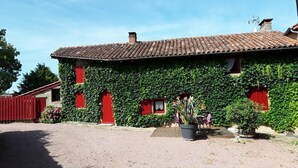 A building with a tiled roof, red doors, and a gravel driveway. - La Rose des Vents - JALOGNY (JALOGNY)