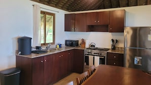 A kitchen with wooden cabinets, a stainless steel refrigerator, a stove, and a ceiling fan. - Stunning Beachfront Home near Cambutal Beach Break (Ave María)