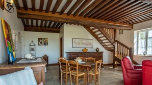 Un espace repas avec des meubles en bois, un escalier et des œuvres d’art accrochées aux murs.