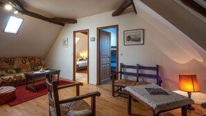 Une pièce mansardée chaleureuse avec un plafond en bois, un canapé rouge, une table à manger avec des chaises et une lampe.
