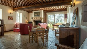 Un salon chaleureux avec une cheminée, des meubles en bois et une grande fenêtre donnant sur l’extérieur.