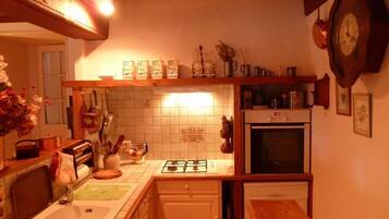 A kitchen with a gas stove, oven, and dishwasher. There is a sink, a wooden countertop, and a clock on the wall.