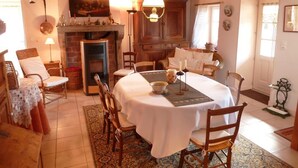 A dining room with a round table, chairs, a fireplace, and wooden beams on the ceiling. - La Randonnée - FLEY - Gîte (FLEY)