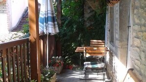 A covered outdoor seating area with wooden benches and tables, surrounded by stone walls and potted plants. - La Randonnée - FLEY - Gîte (FLEY)