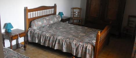 A bedroom with a wooden bed, a nightstand, a chair, and a wardrobe.