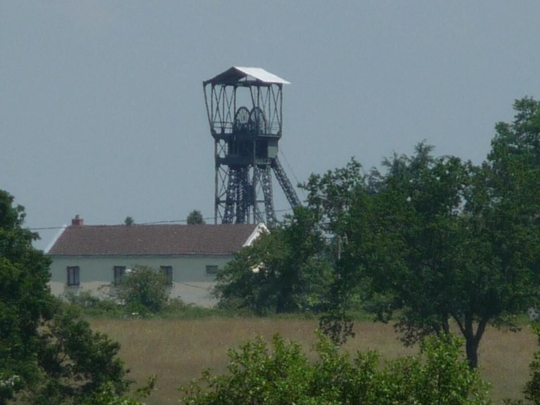 A building with a tower structure and a house with a red roof in the foreground.