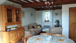 A cozy room with wooden furniture, a dining table with a lemon-patterned tablecloth, and a chandelier. - Les Lilas - COUCHES - Gîte (COUCHES)