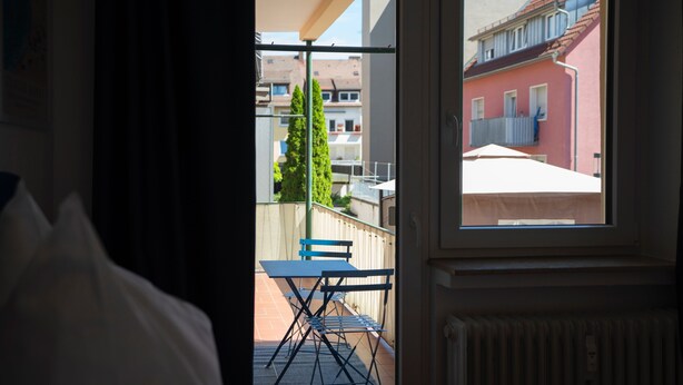 A room with a view of a balcony, a table, and chairs.