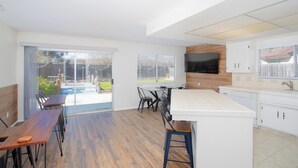 Una cocina moderna con una isla grande, armarios blancos y un televisor de pantalla plana.
