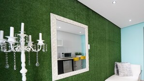 Una sala de estar moderna con un muro de césped artificial verde, un sofá blanco, una silla blanca y una araña.