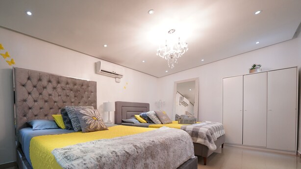 Un dormitorio moderno con una cama grande, una cama más pequeña, un armario y una araña.