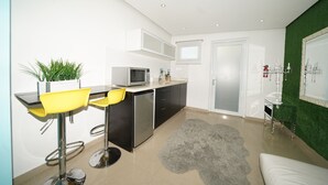 Una cocina moderna con comedor, que incluye un taburete de bar, un microondas y un refrigerador.