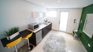 Cocina moderna con microondas, fregadero y armarios. Hay una planta en la encimera y una alfombra mullida en el suelo.