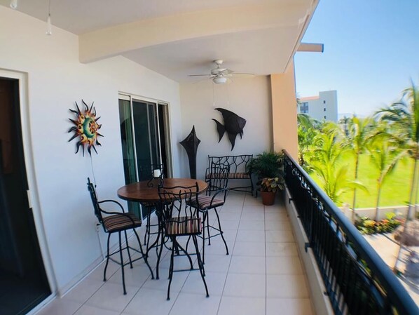 A balcony with a round table and chairs, a ceiling fan, and decorative wall art.