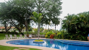 A swimming pool with lounge chairs and palm trees. - El Tigre Green Bay I Condos (Nuevo Nayarit)
