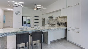 A modern kitchen with a marble countertop, white cabinets, and a ceiling fan. - El Tigre Green Bay I Condos (Nuevo Nayarit)