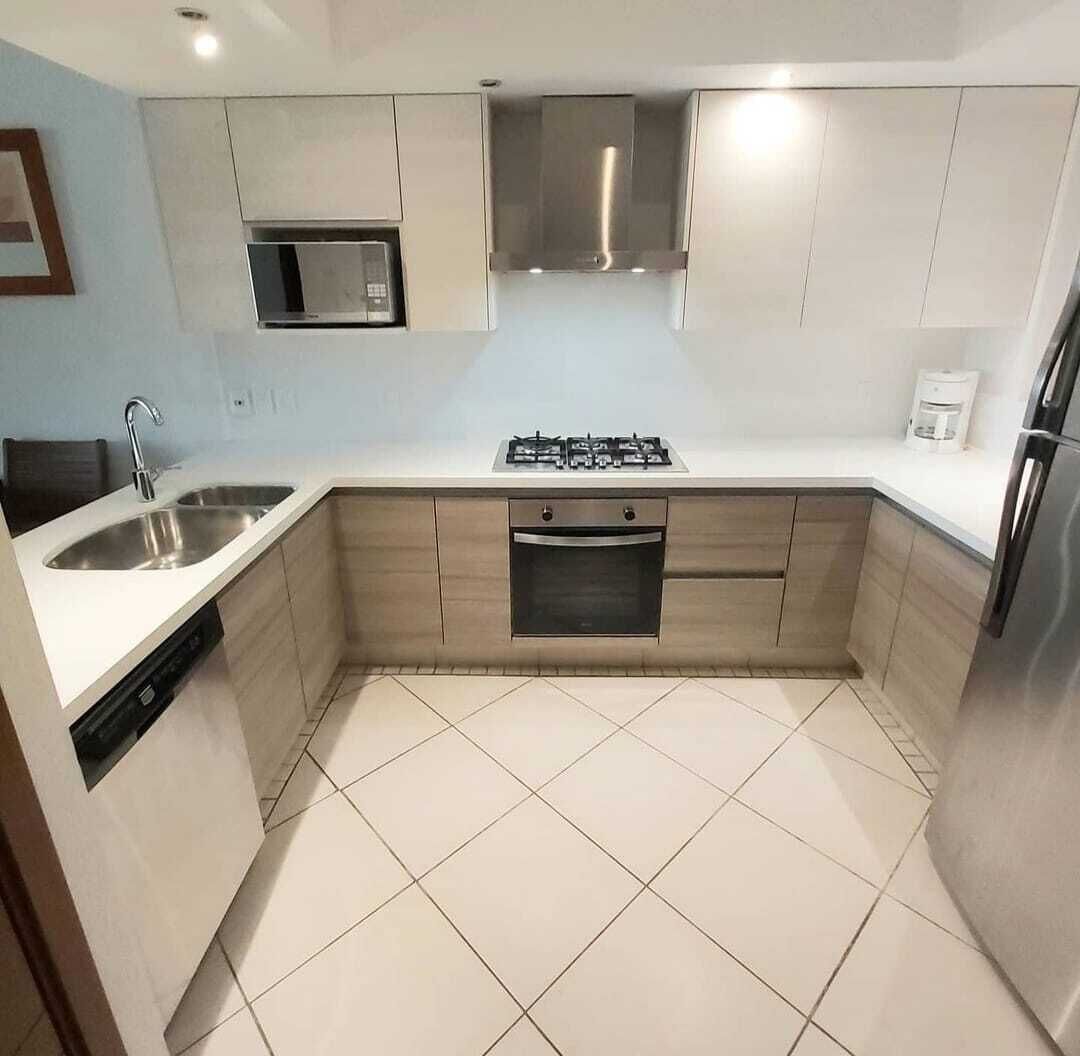 A modern kitchen with a built-in oven, stainless steel sink, and a microwave.