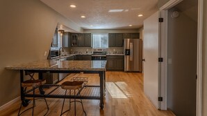 A modern kitchen with granite countertops, stainless steel appliances, and a central island with stools.