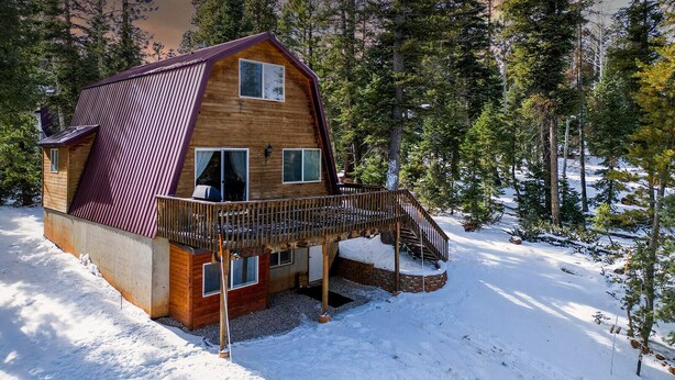 A wooden cabin with a metal roof, a balcony, and a staircase leading to the entrance.
