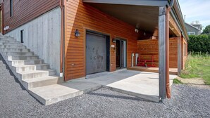 Une maison moderne dotée d’une porte de garage en béton, d’un revêtement extérieur en bois et d’un porche abrité.