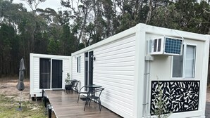 Una casa móvil con terraza, mobiliario de exterior y una planta en maceta.