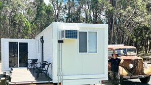 Una casa móvil con un patio, una puerta corrediza y un vehículo estacionado cerca.