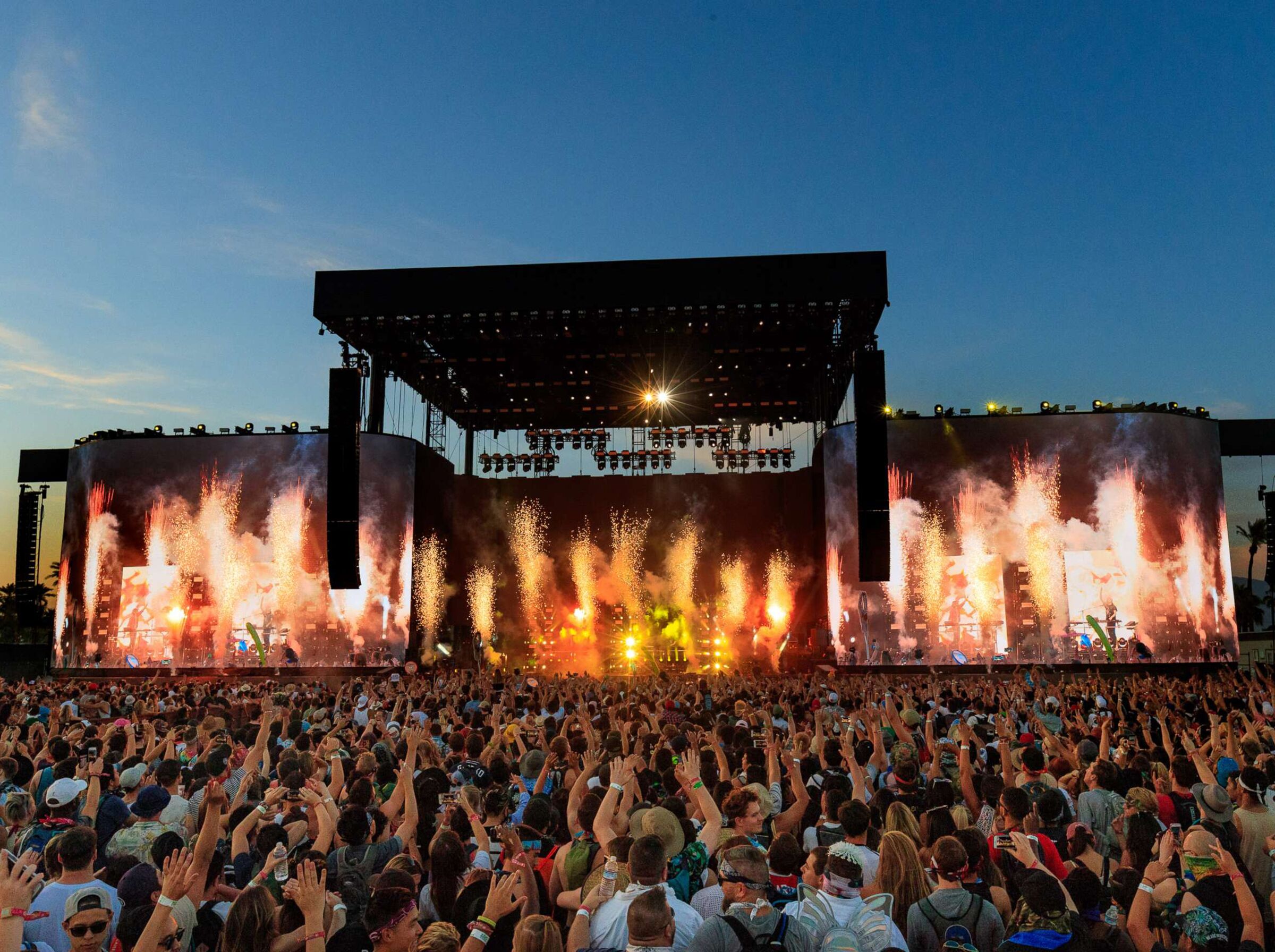 A large outdoor concert stage with a crowd of people in front.