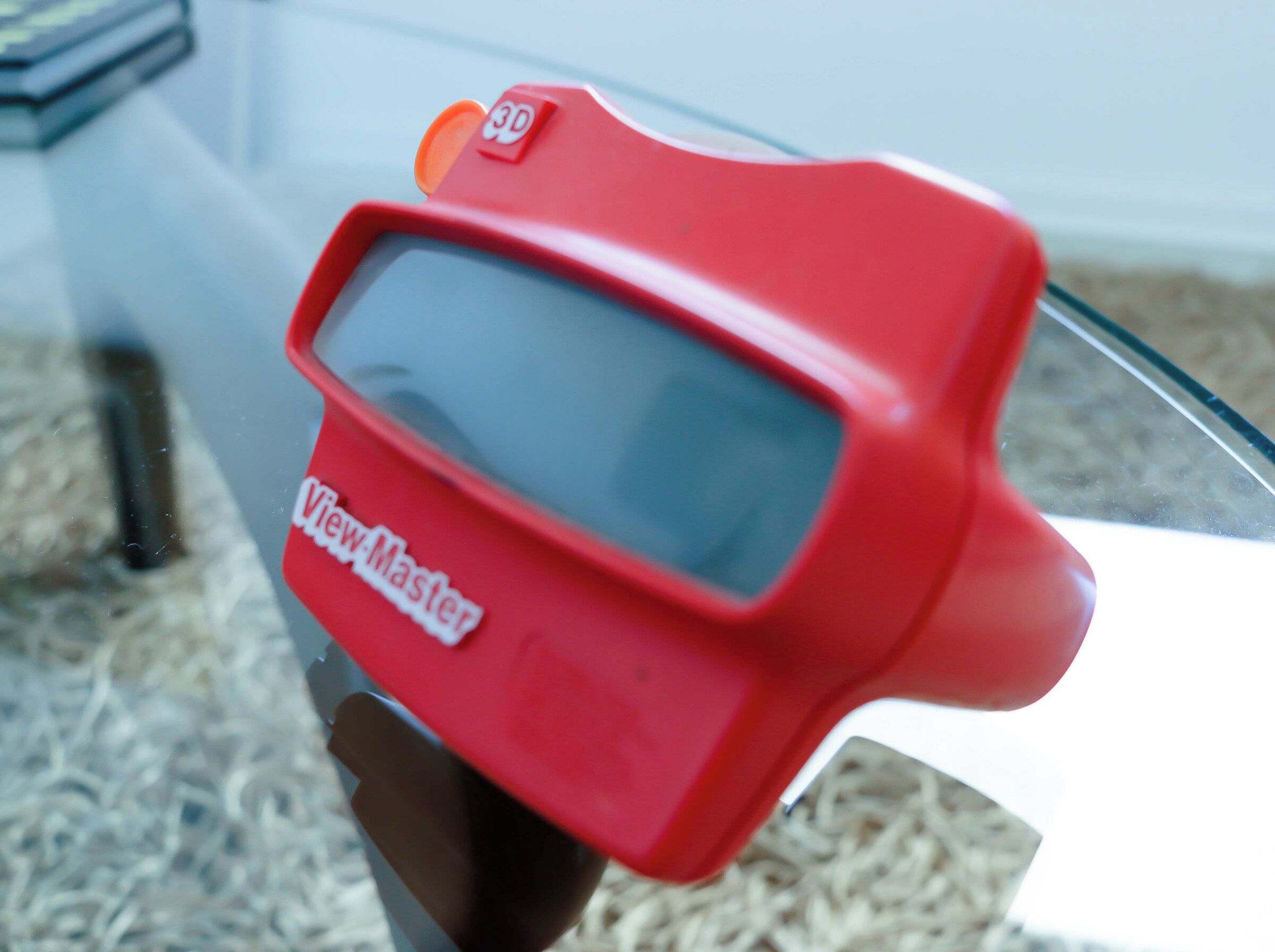 En rød ViewMaster 3D-fremviser fastgjort til en bilrude.
