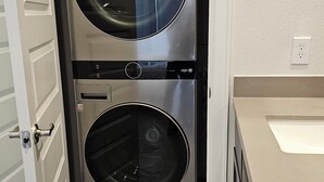 A double-door laundry room with stainless steel appliances, a white door, and a beige countertop.