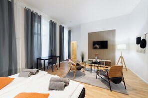 Een moderne hotelkamer met een bed, twee stoelen, een bureau, een televisie en een lamp.