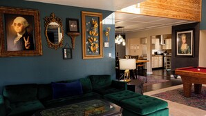 Una sala de estar con un sofá verde, una mesa de centro y una mesa de billar.