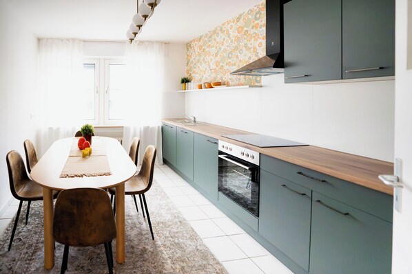 A modern kitchen with a dining table, chairs, and a built-in oven.