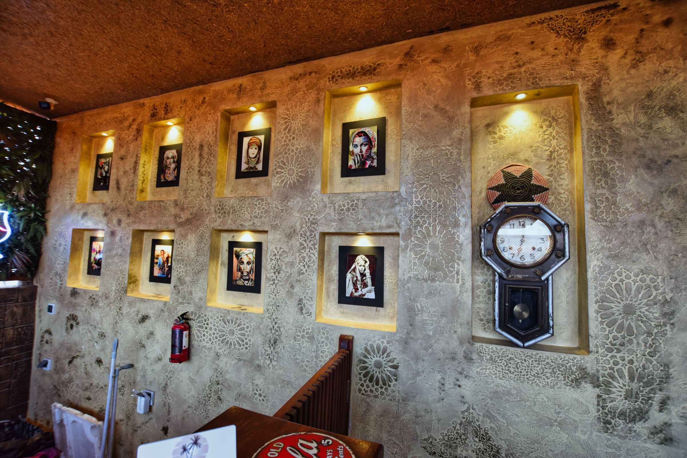 A wall with framed artwork and a large clock.