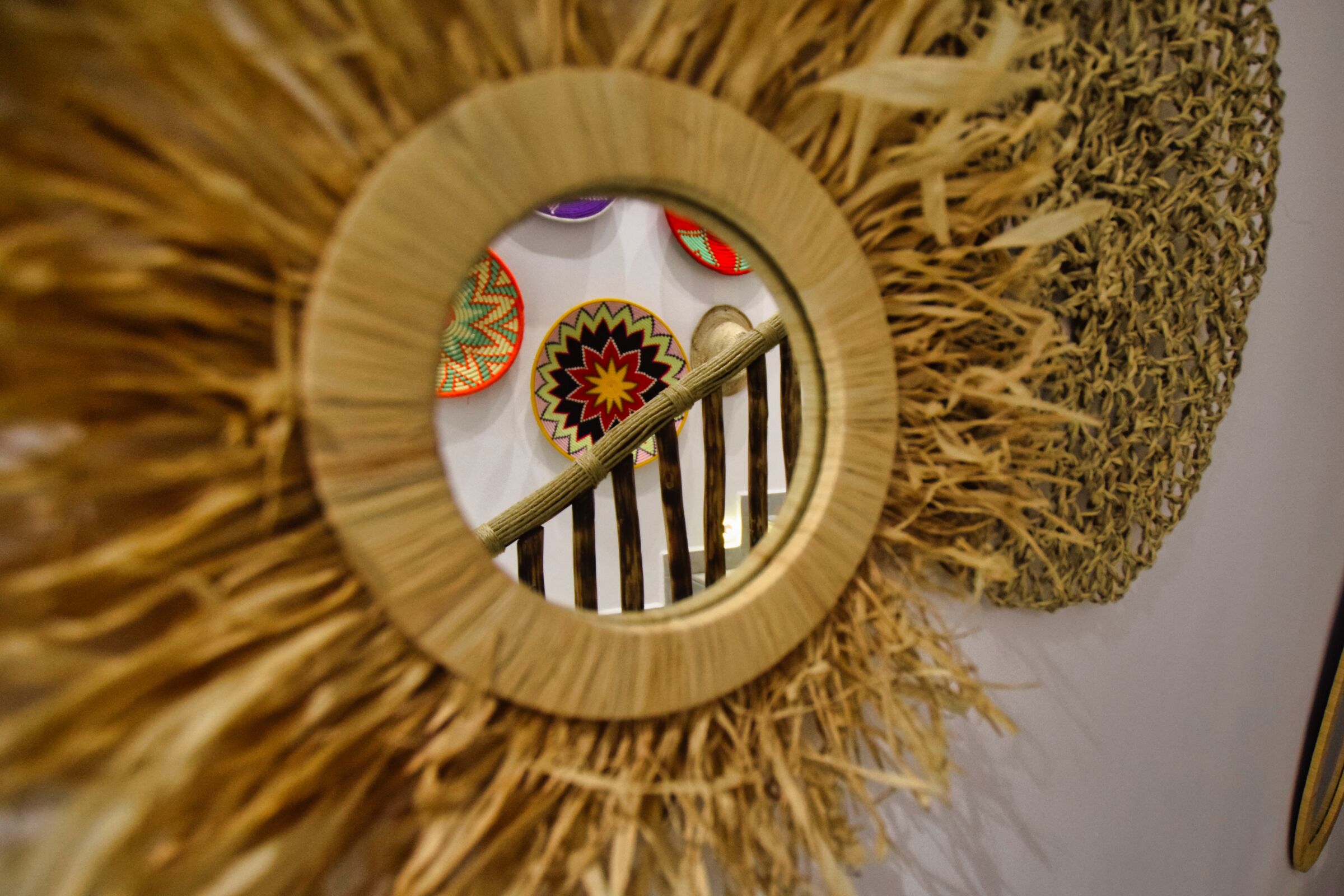 A circular wall decoration with a central metal gate, surrounded by a sunburst pattern and textured fabric.