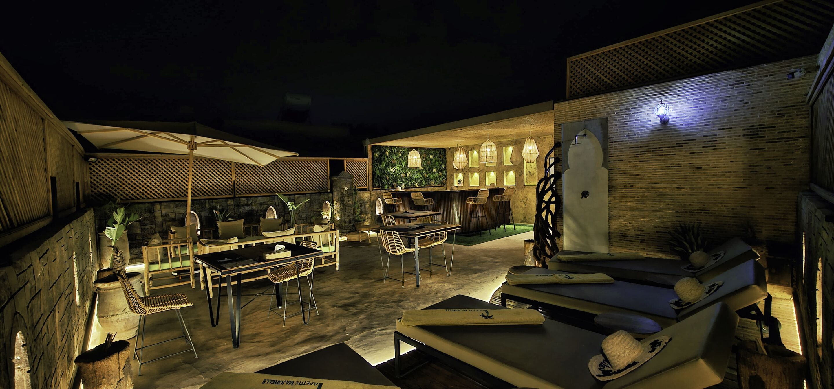 An outdoor dining area with tables and chairs, a bar area, and lounge chairs.