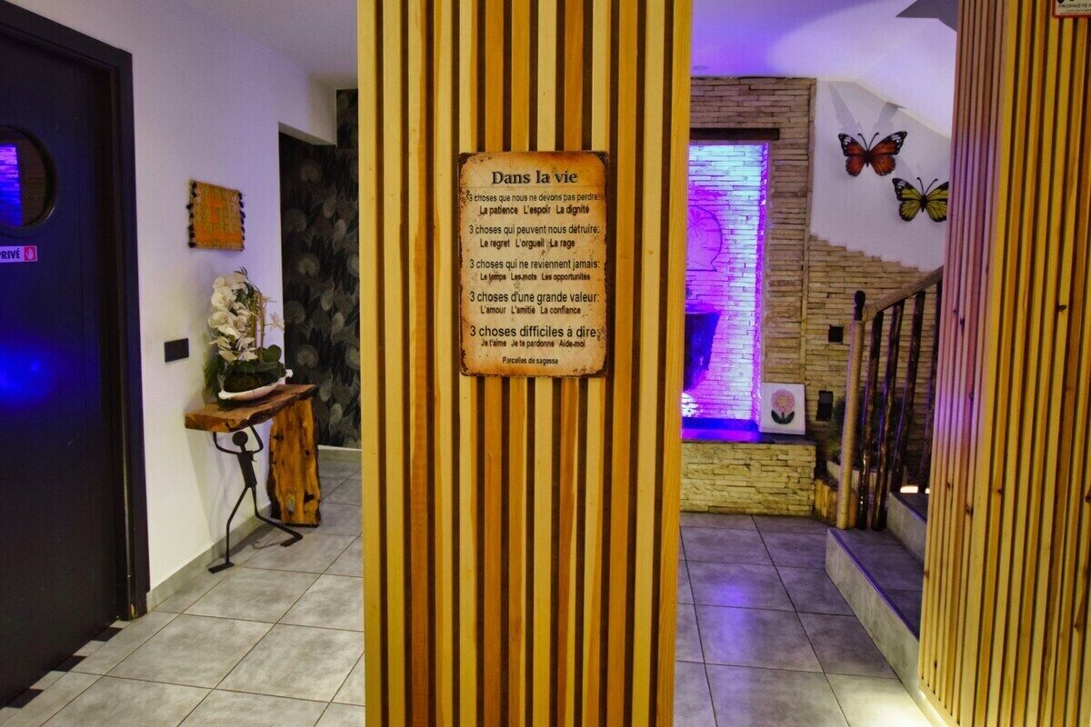 A hallway with vertical wooden slats, a sign with French text, a staircase with a butterfly decoration, and a wall with a stone pattern.