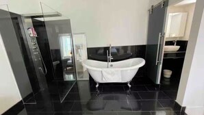 A modern bathroom with a freestanding bathtub, black tiled floor, and a glass shower enclosure. - Delightful Haven, Center of Villefranche  (Villefranche-sur-Mer)