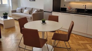 A modern kitchen with white cabinets, a black range hood, and a dining area with a round table and four chairs. - Delightful Haven, Center of Villefranche  (Villefranche-sur-Mer)