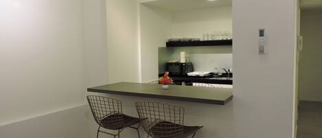 A modern kitchen with a bar area, two wireframe bar stools, and a countertop.