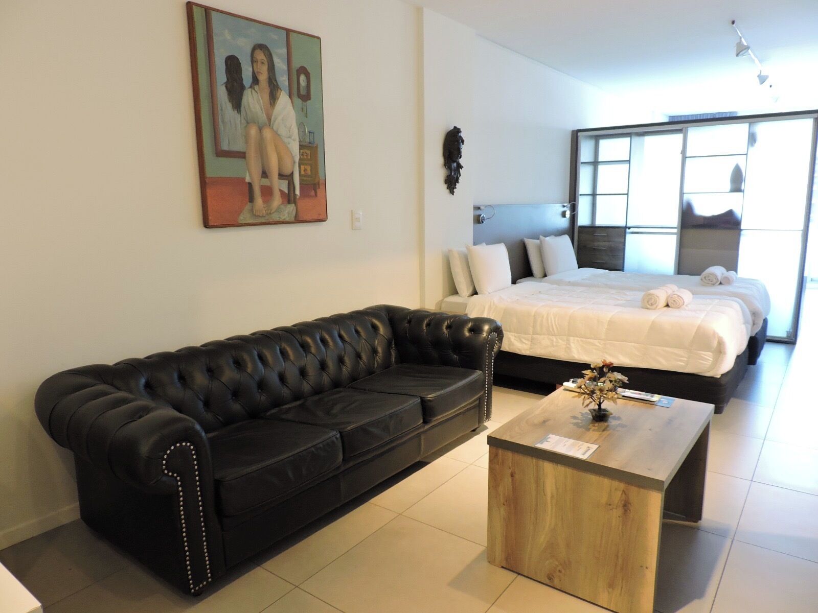 Ein modernes Schlafzimmer mit einem großen Bett, einem schwarzen Ledersofa und einem Holztisch.