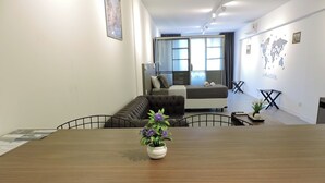 A modern, well-lit room with a large wooden table, a sofa, and a bed in the background. - Rivadavia Apartments (Buenos Aires)