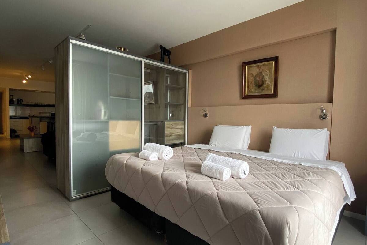 A hotel room with a bed, a wardrobe, and a bathroom visible in the background.